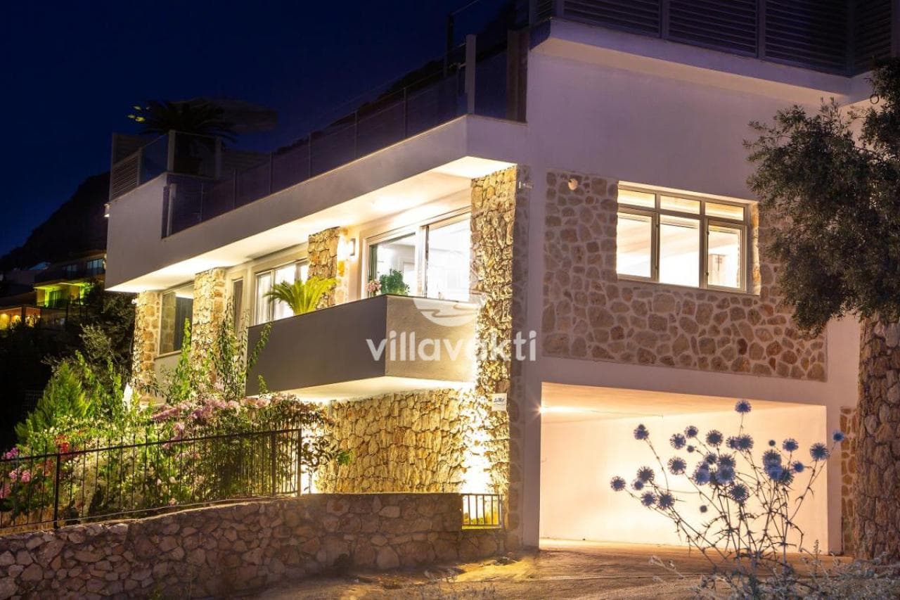 Akşam aydınlatmalı taş detaylı villanın dış cephesi.
