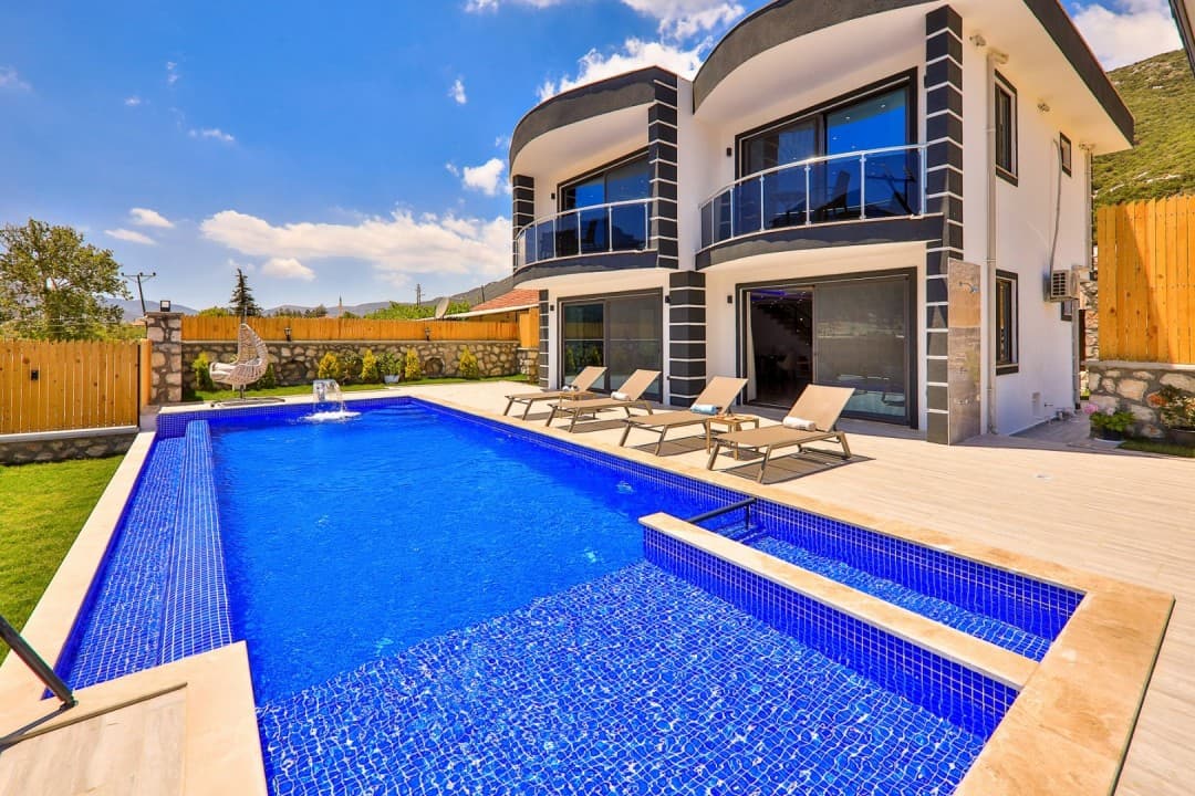 Mavi havuzlu, iki katlı, siyah beyaz dış cepheli modern villanın dış görünümü.