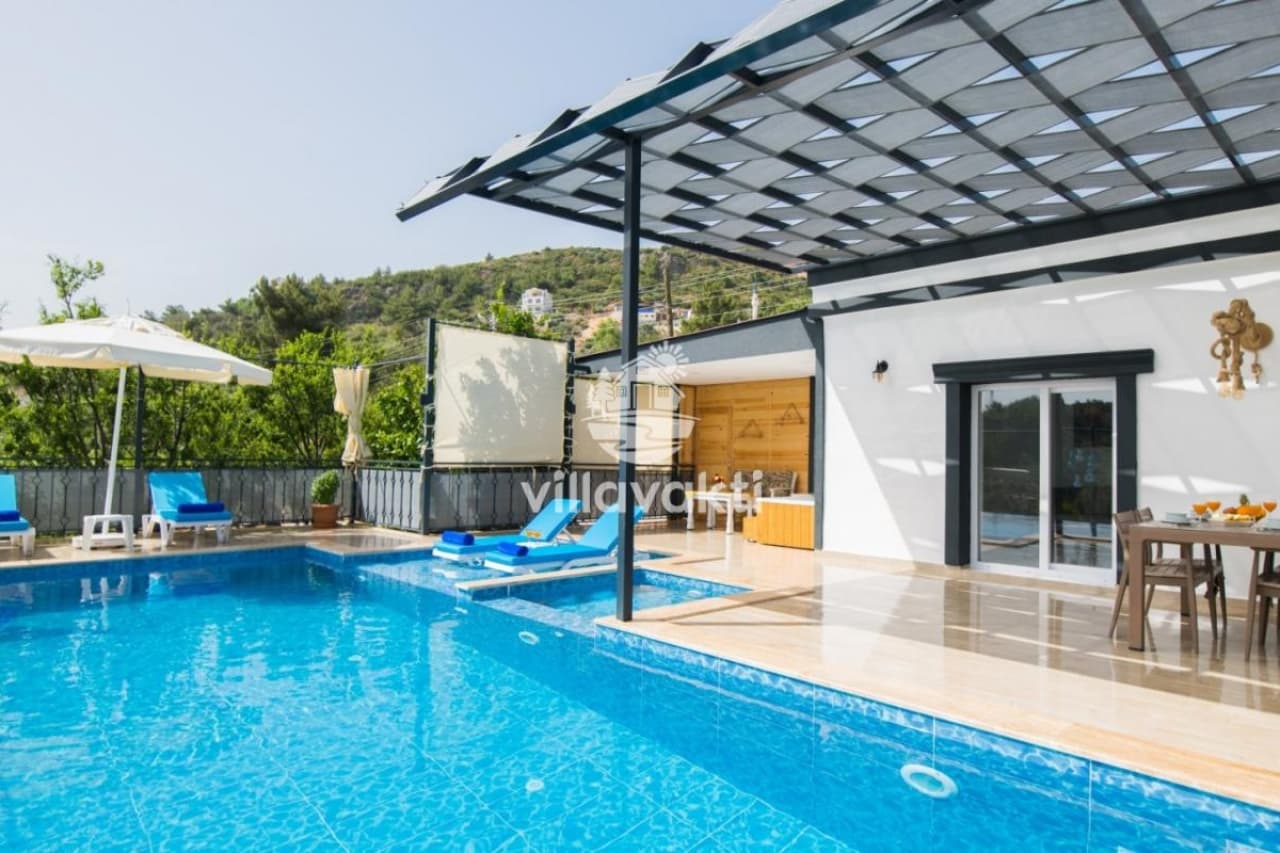 Açık havuzlu, şezlonglu ve dağ manzaralı villa terası.