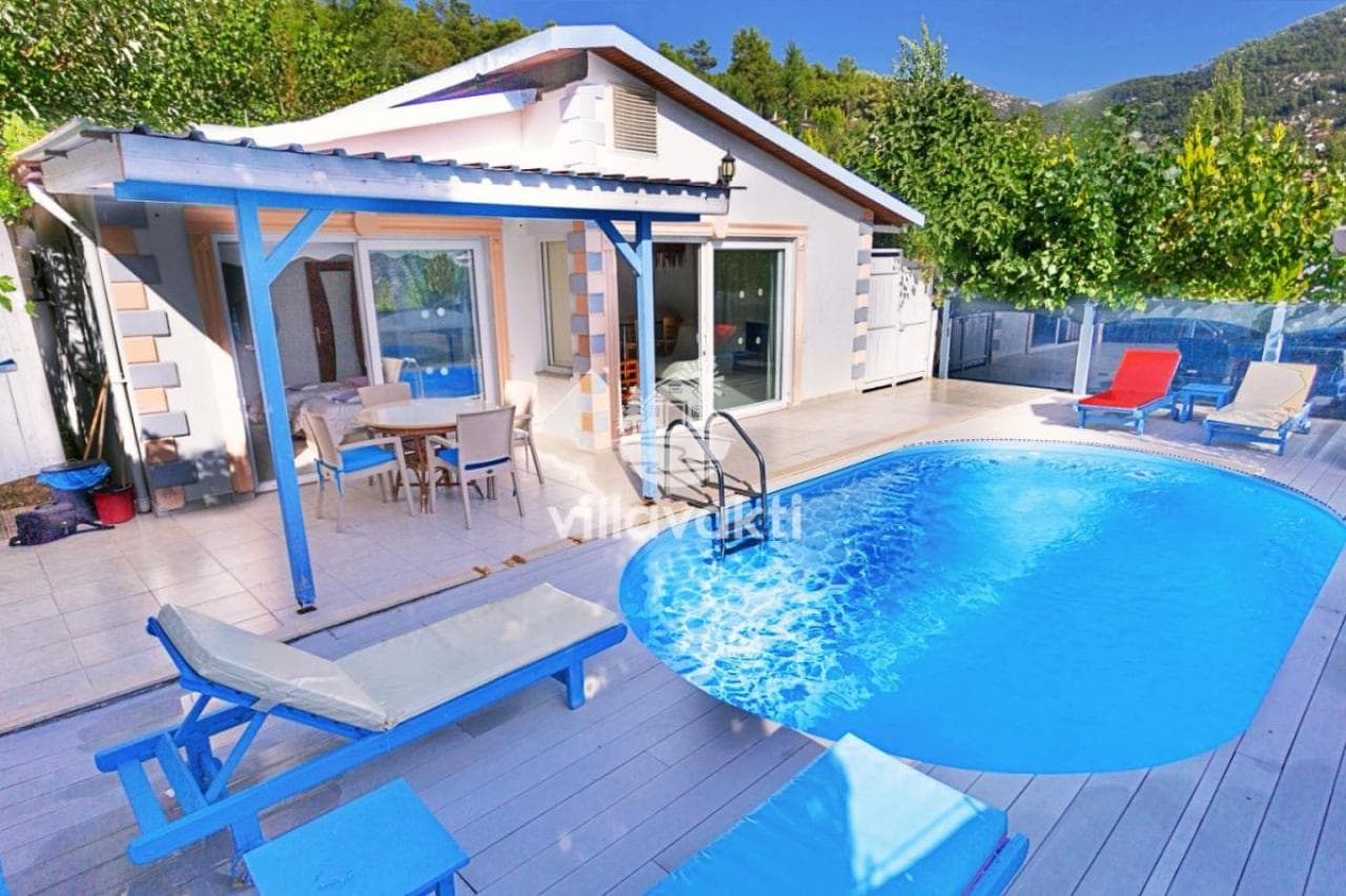 Bahçesinde havuz ve şezlonglar bulunan tek katlı beyaz villa.