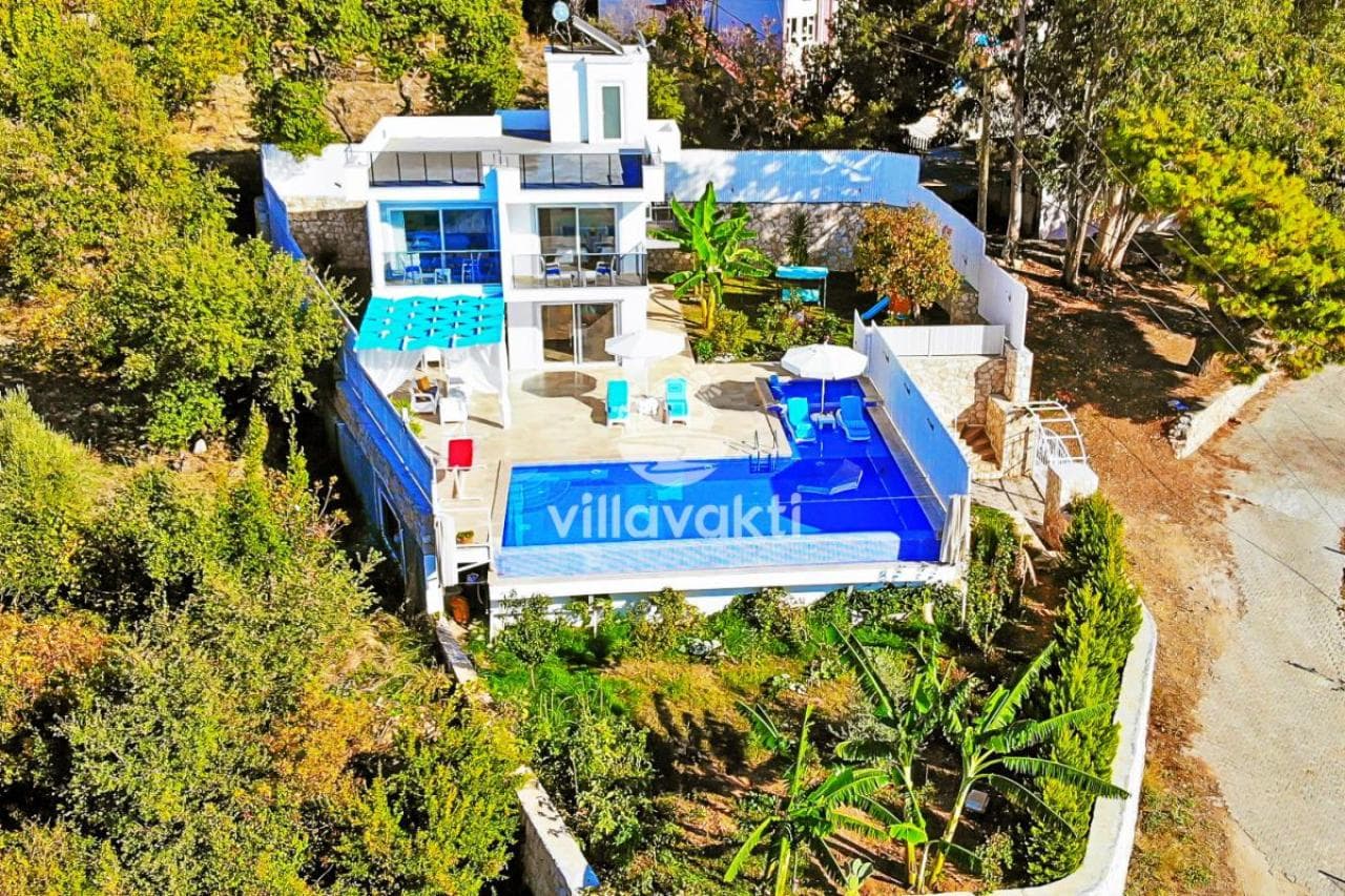 Bahçesinde havuz ve şezlonglar bulunan beyaz renkli çok katlı villa.