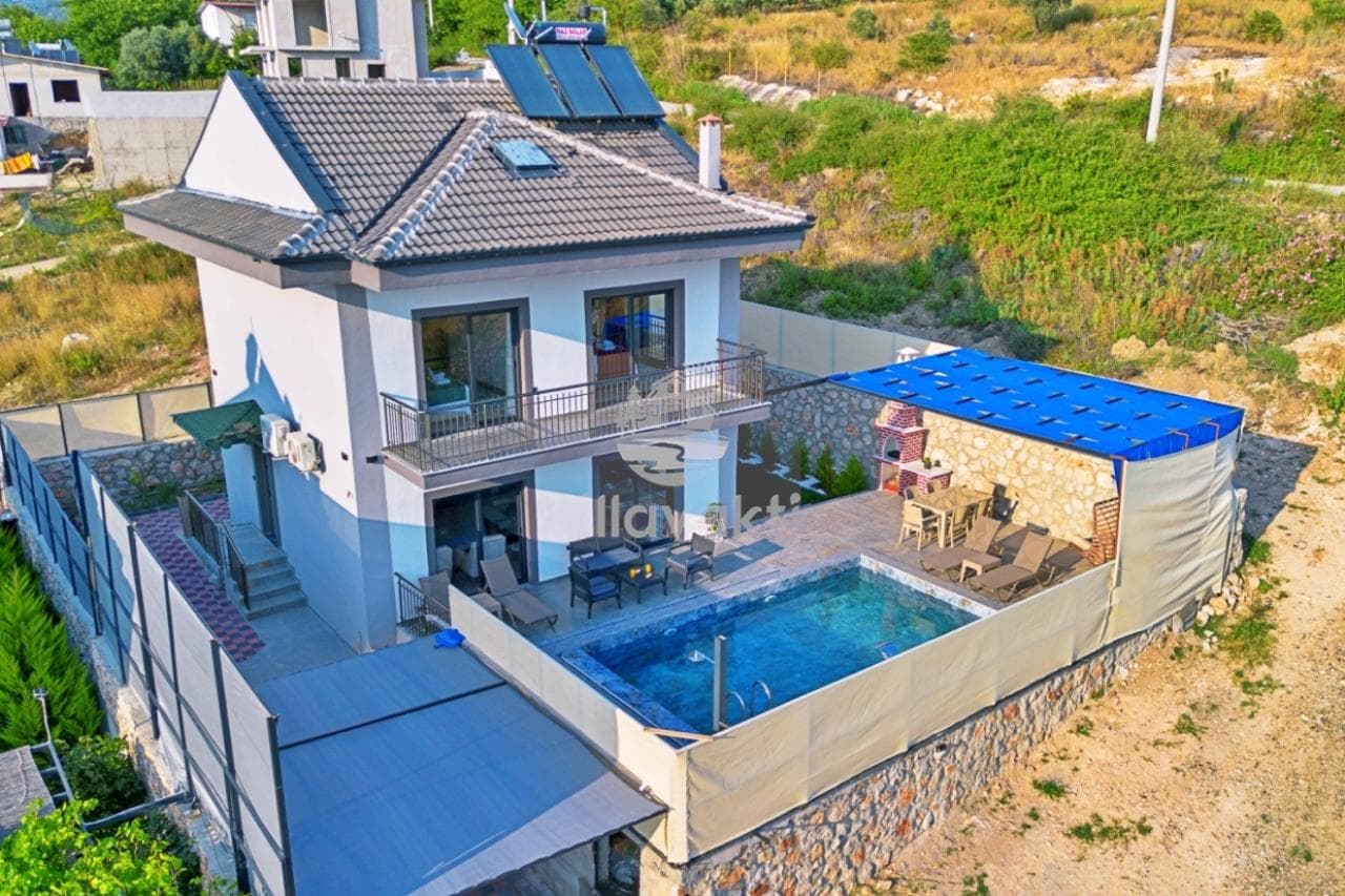 Önünde yüzme havuzu ve şezlonglar bulunan iki katlı beyaz dış cepheli villa.