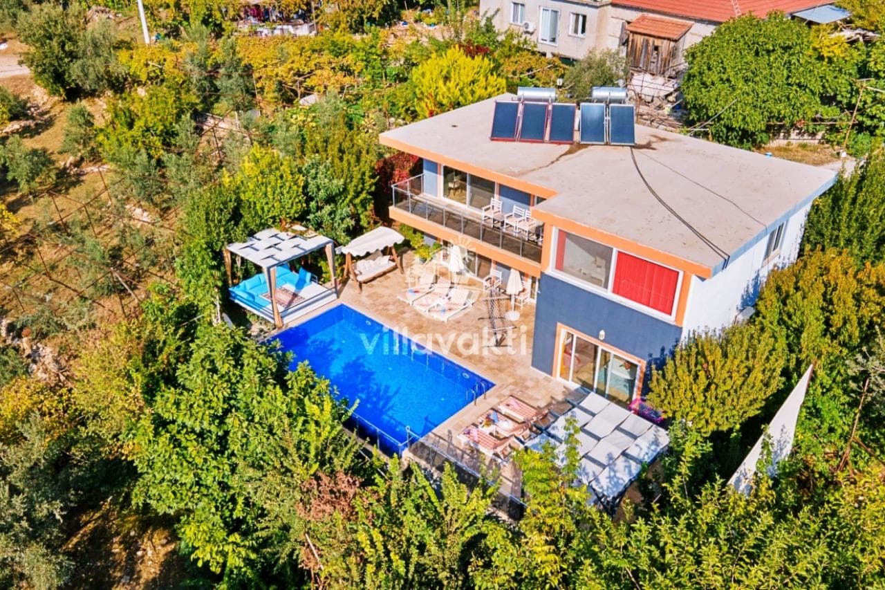 Ağaçlar arasında yer alan villanın havuzu ve bahçesi havadan görünüyor.