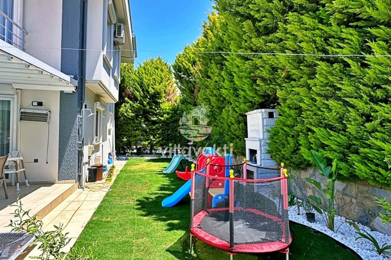 Villa bahçesinde çocuk oyun alanı, trambolin, kaydıraklar ve taş barbekü bulunuyor.