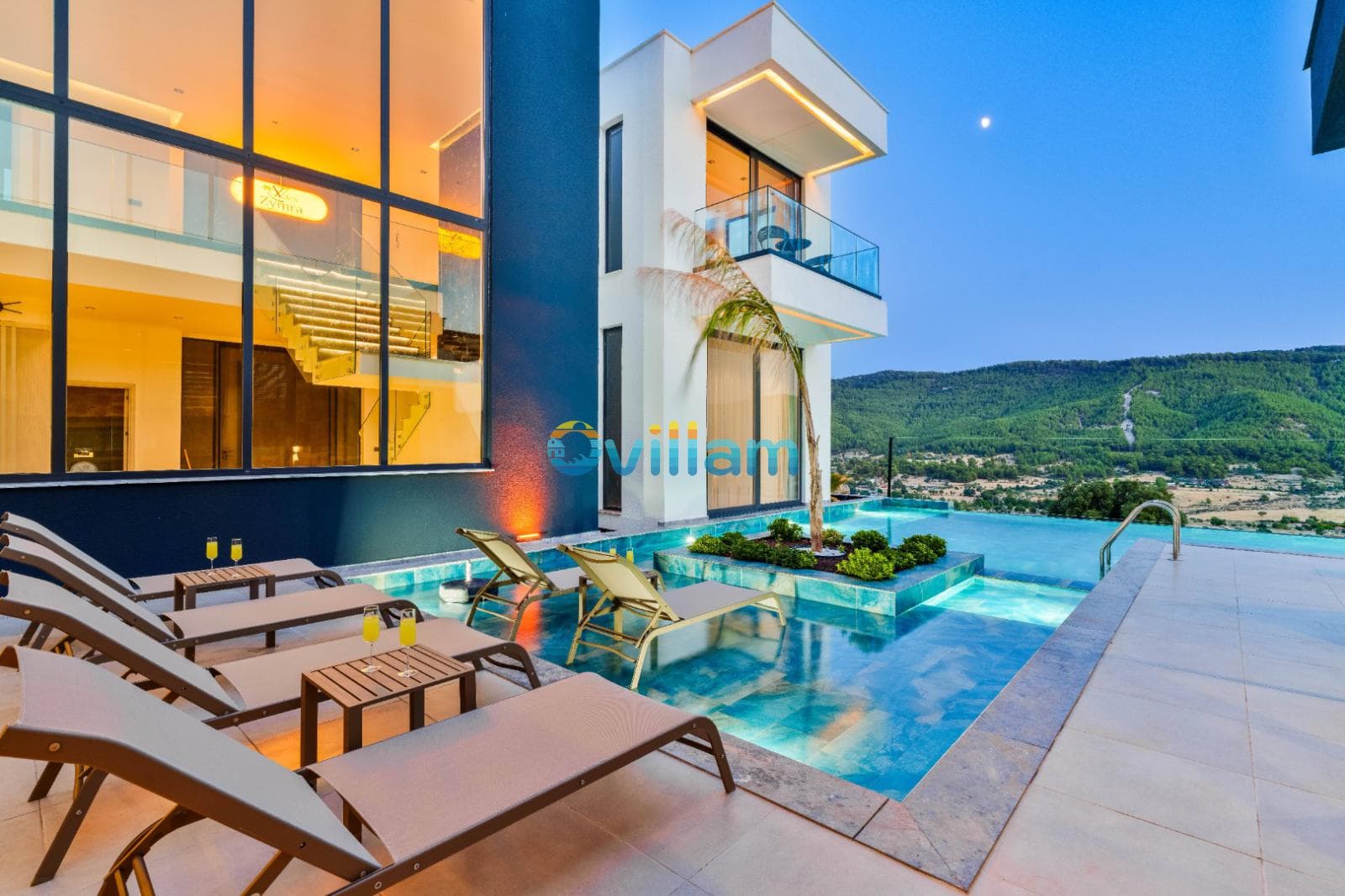 Havuz kenarında sıralanmış şezlonglar, özel yüzme havuzu ve akşam vakti dağ manzaralı villa.